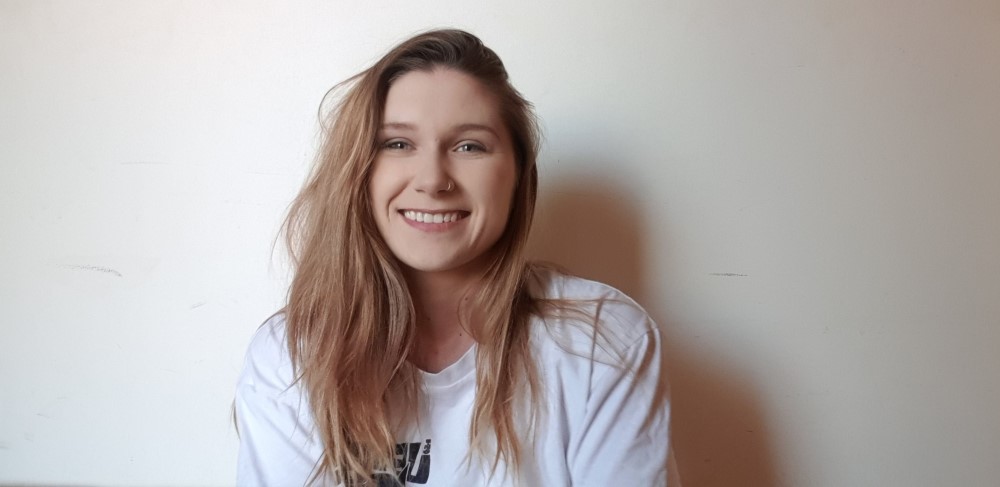 Young woman smiling at camera in front of white wall