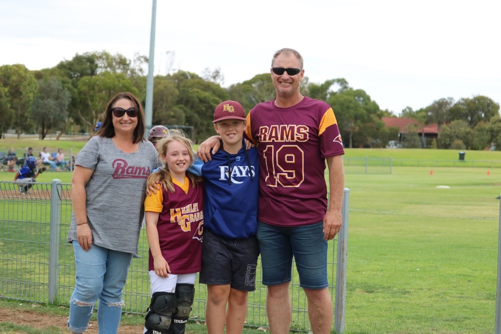 A family of four posing for the camera in baseball gear