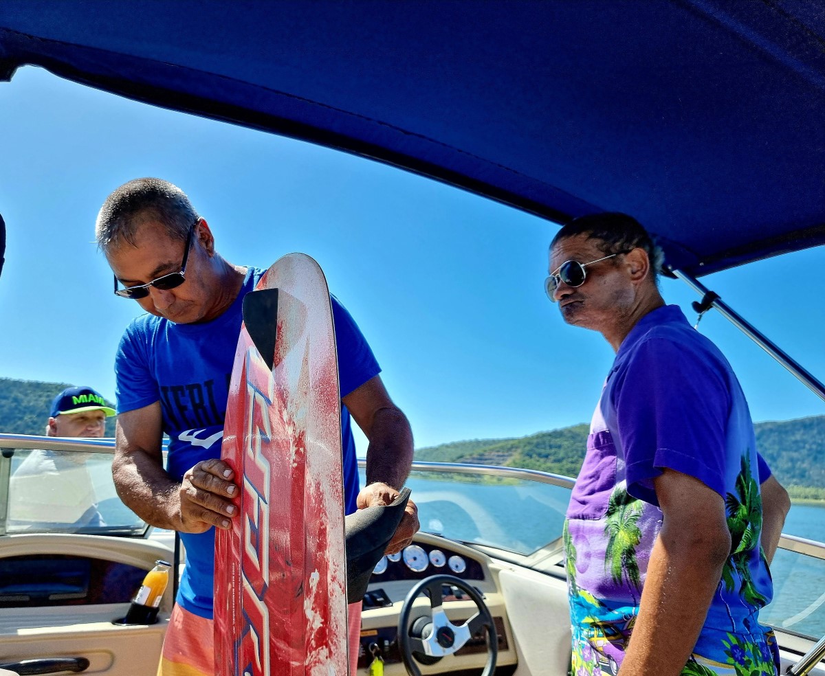 Two middle aged men on a boat, holding a wakeboard