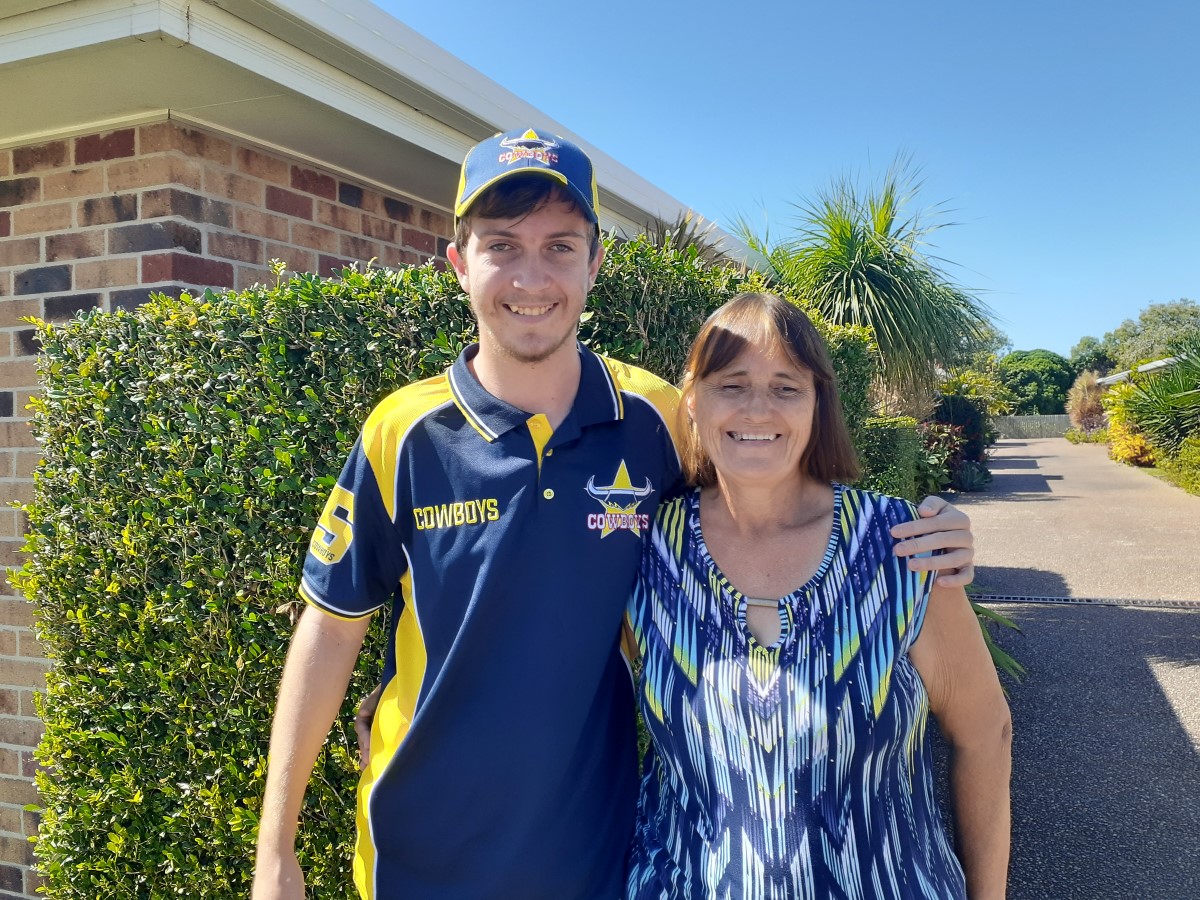 Young man and middle aged woman hugging and posing for picture outside