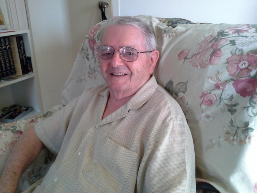 Senior man sitting on couch, smiling at camera