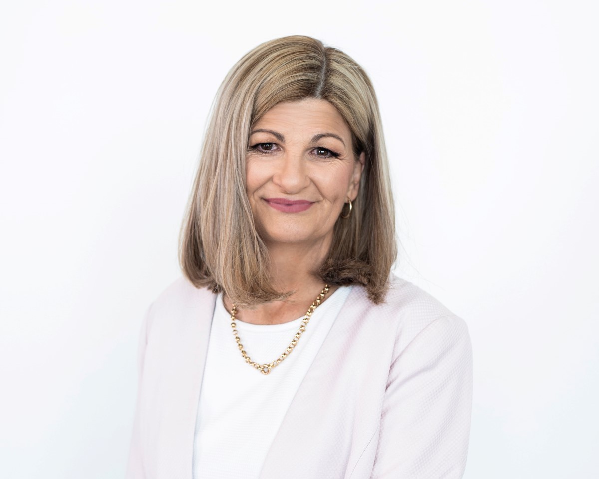 Head shot of blonde woman in his 50s wearing a pink cardigan