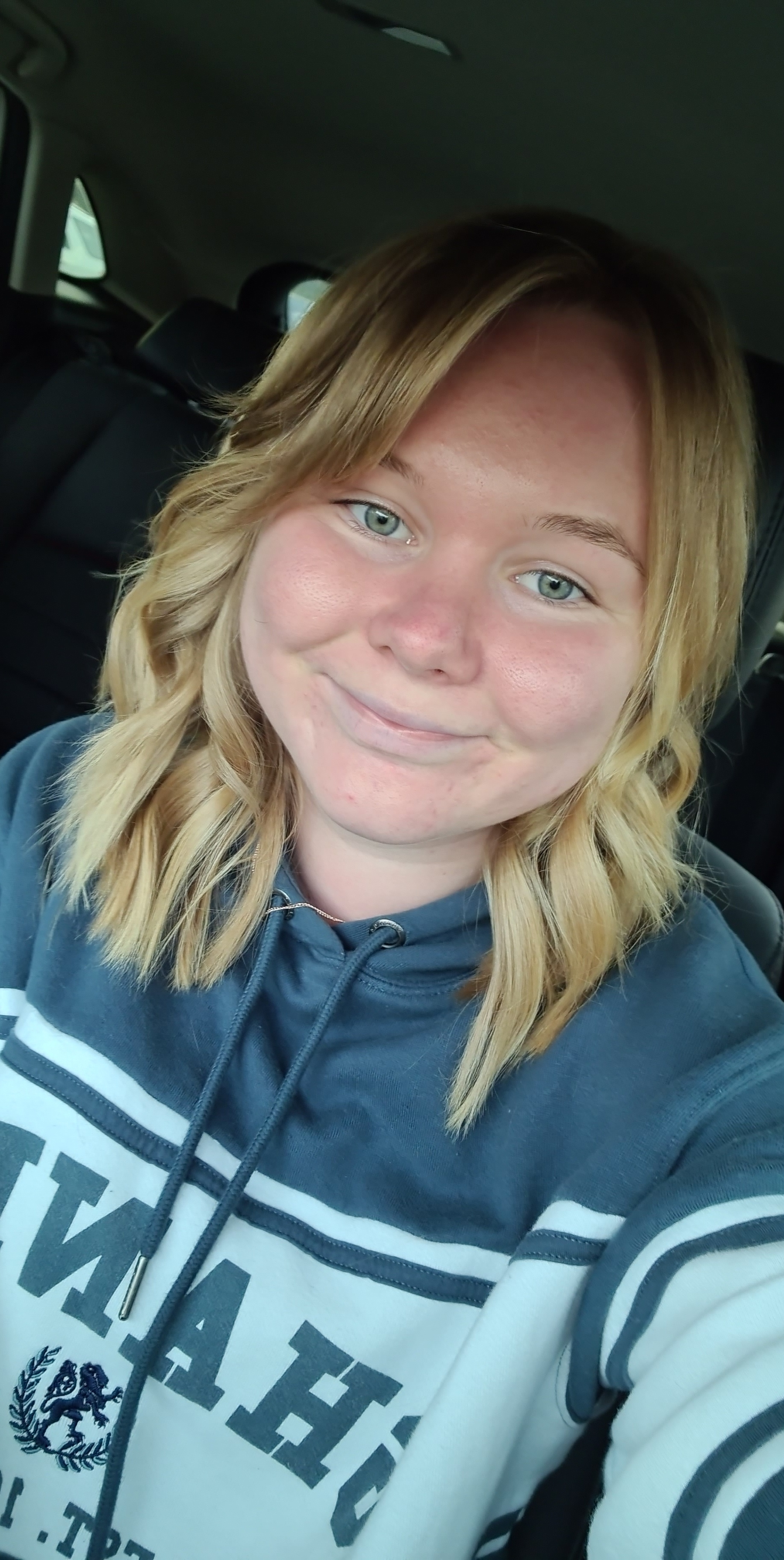 Young blonde woman taking a selfie in a car