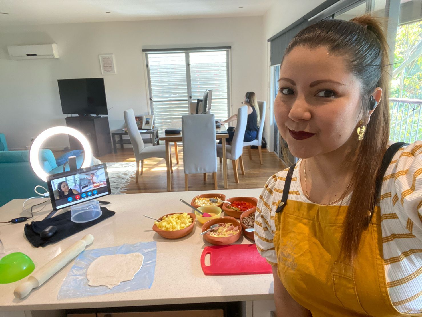 Brunette woman posing at a kitchen bench doing a virtual cooking class