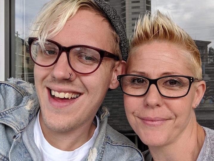 Young man and his mother, both with blonde short hair and glasses, smile for selfie