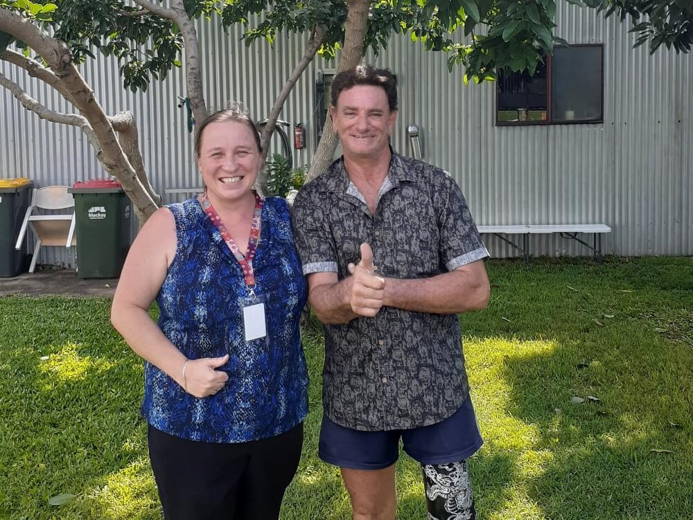 Woman and man with one prosthetic leg doing thumbs up for the camera outside