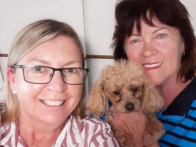 Two women and a dog puppy posing for a selfie