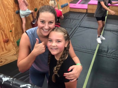 Young woman and little girl posing for camera in indoor rock climbing gym