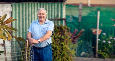 Senior man leaning on fence in garden