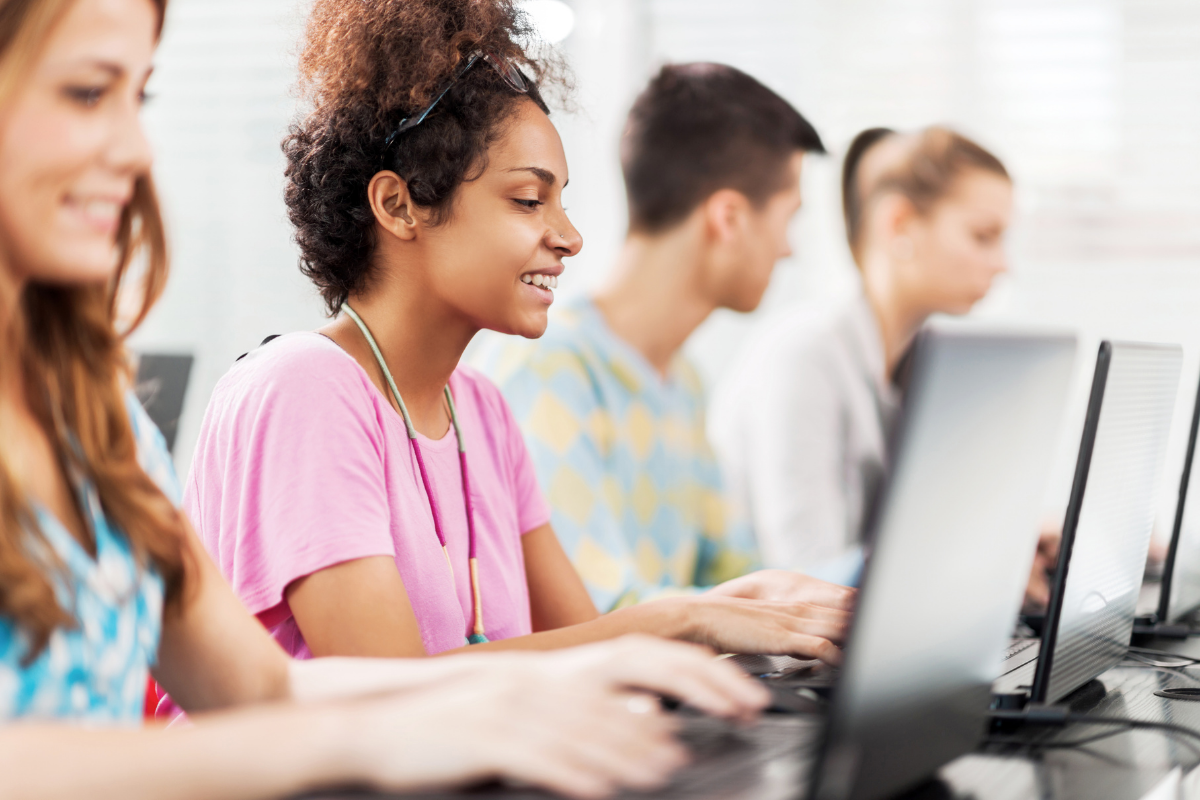 Row of four young adults sitting in front of laptops