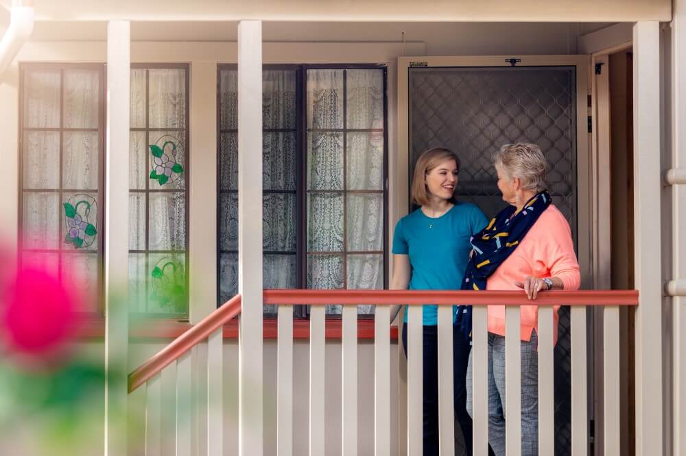 Young woman and senior lady saying goodbye on porch