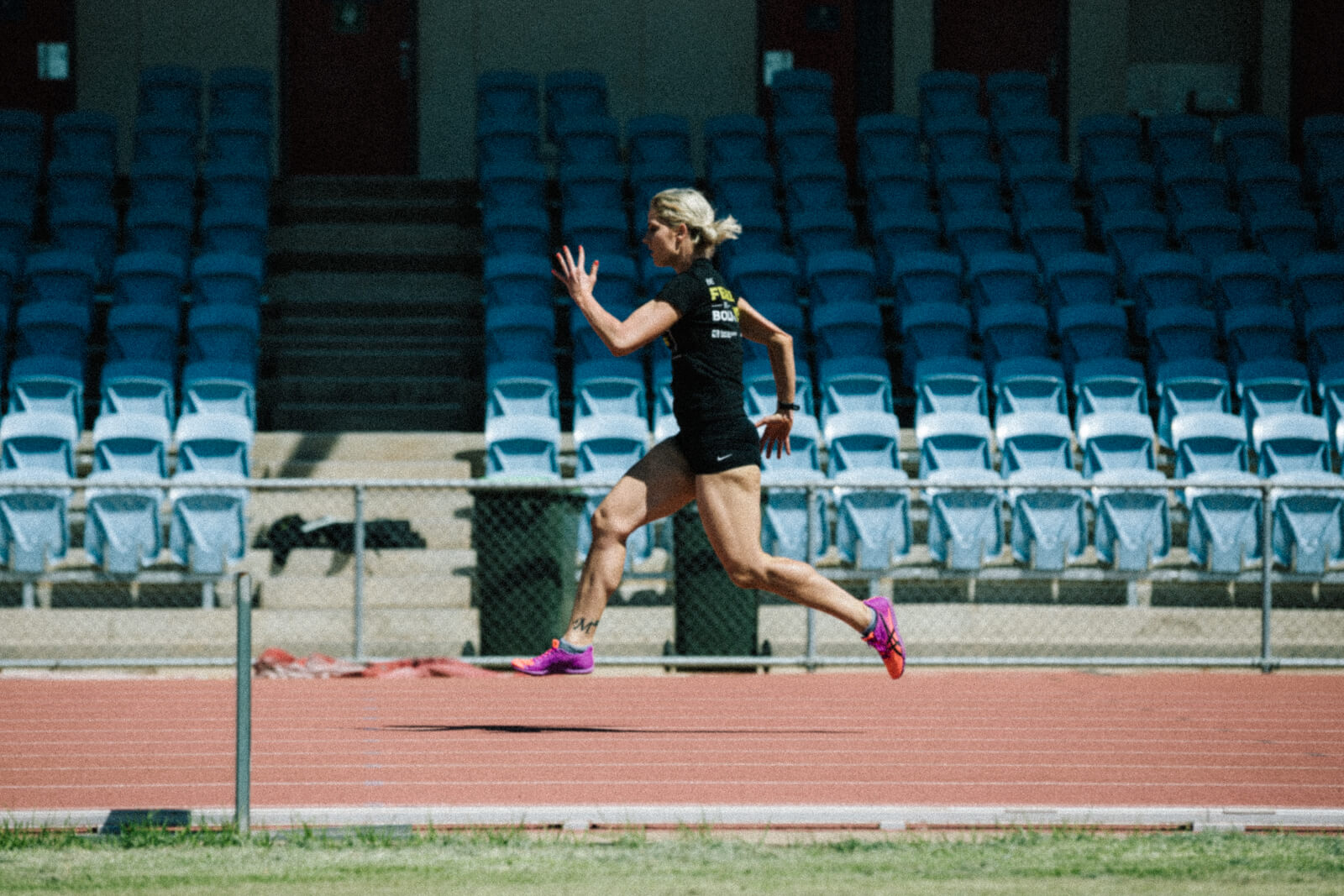 Young blonde woman running on track