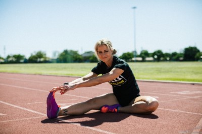 Young blonde woman stretching on track