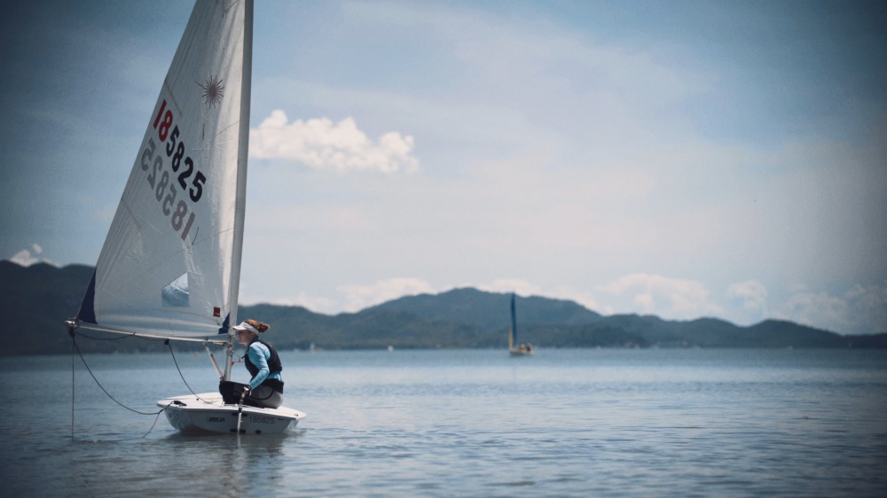 Teenage girl in laser sailboat