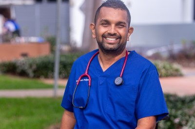 Young Sri Lankan doctor in blue scrubs smiling at camera