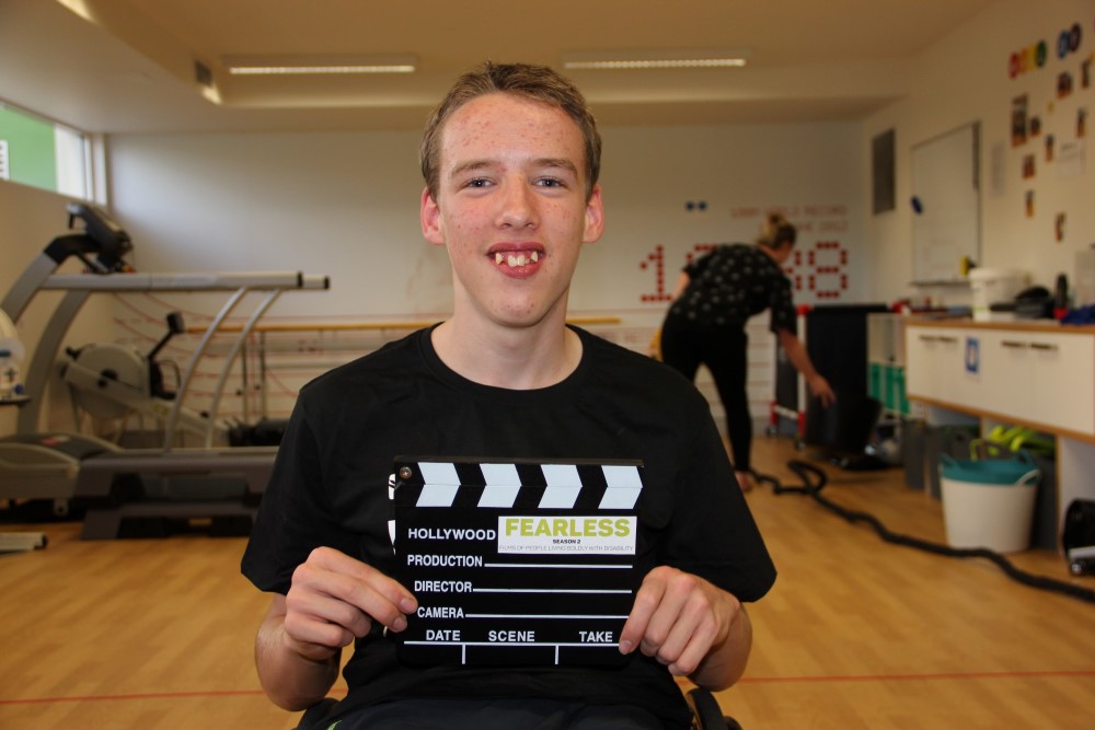 Boy in wheelchair holding a clapboard 