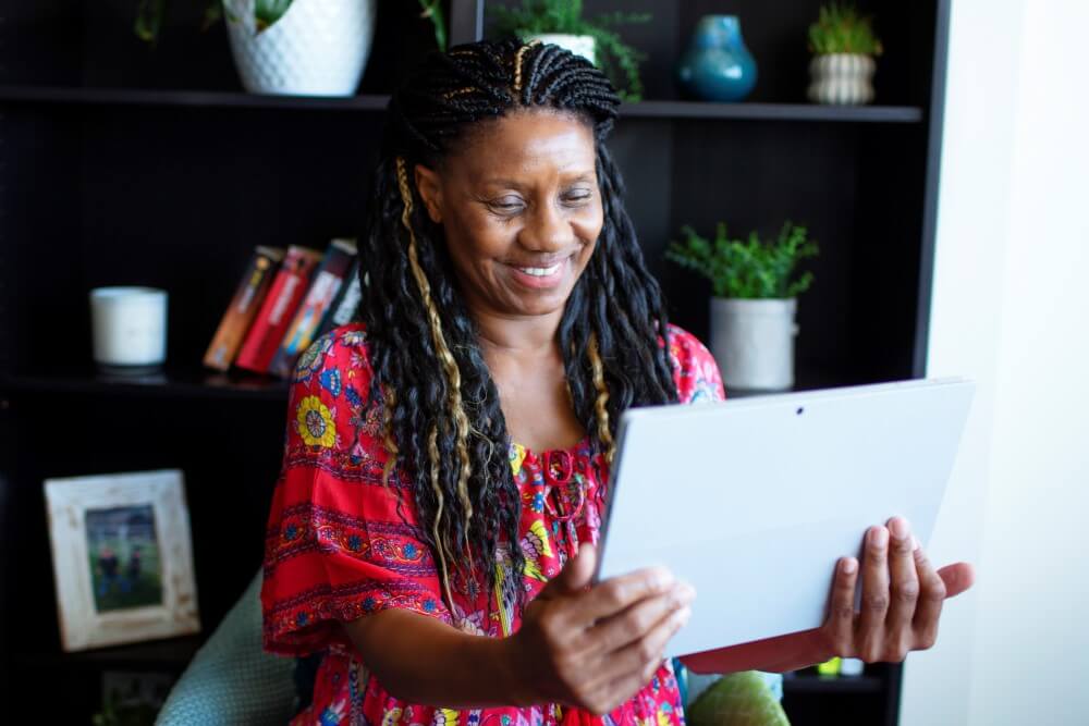 Senior black lady smiling at tablet