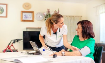 Young nurse taking the blood pressure of elderly lady