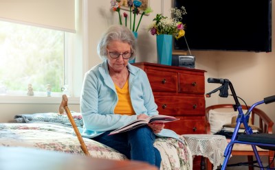 Senior lady sitting on her bed and reading a book