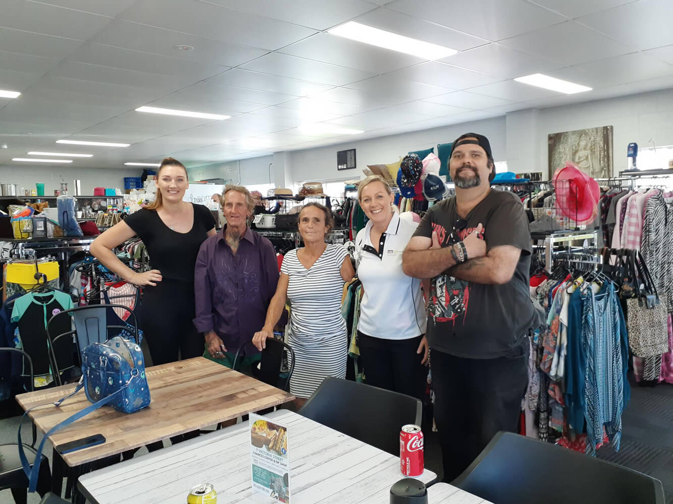 5 people in an op shop. They are smiling and looking toward the camera.