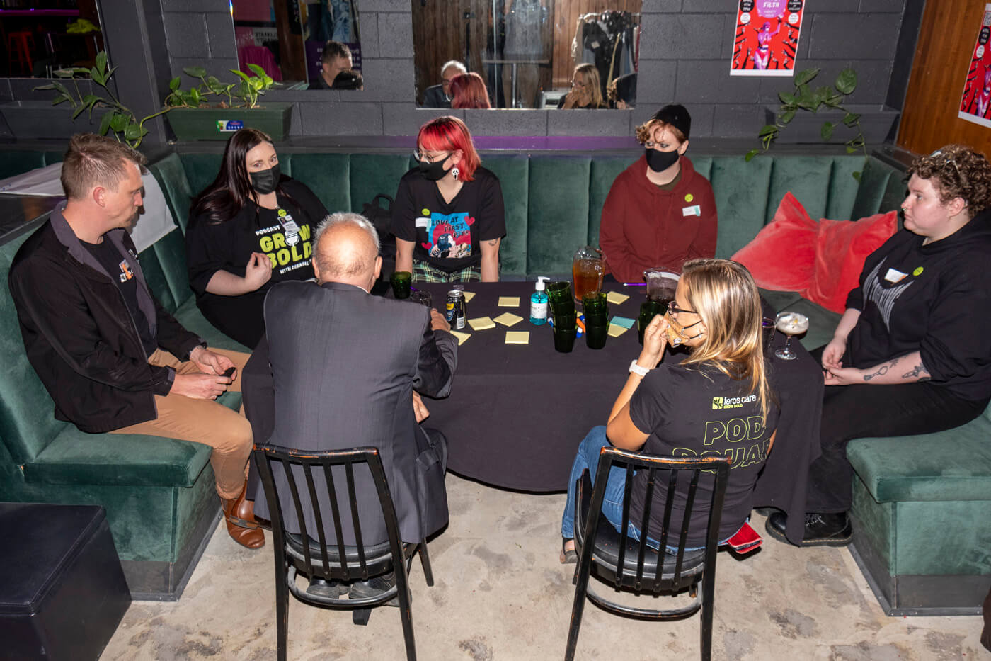 7 people sitting around a table. They are listening to one person speak.