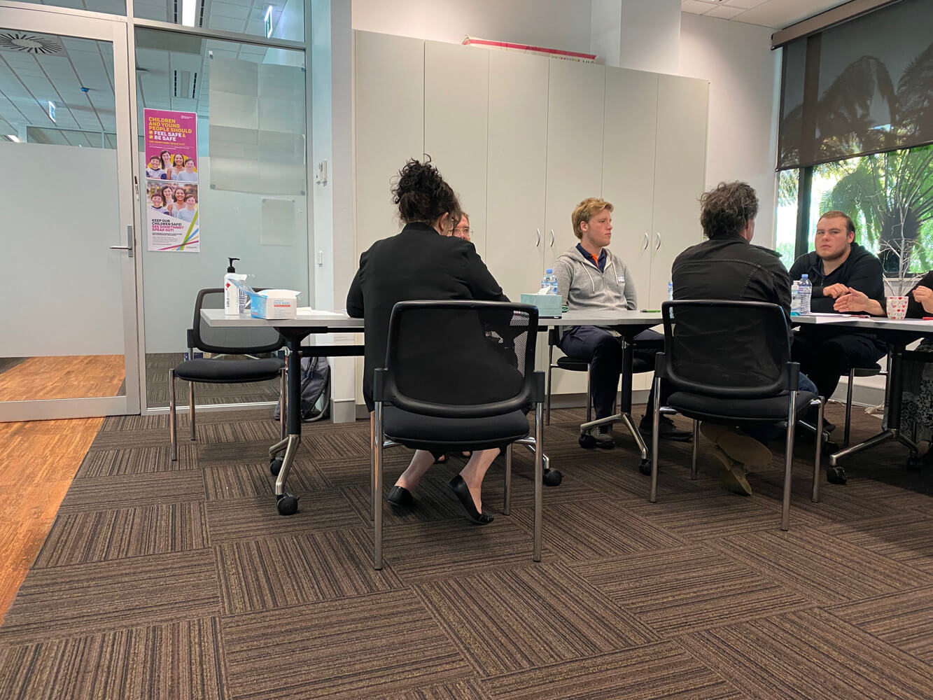 6 people sitting around the table. They are in conversation, not looking at the camera.