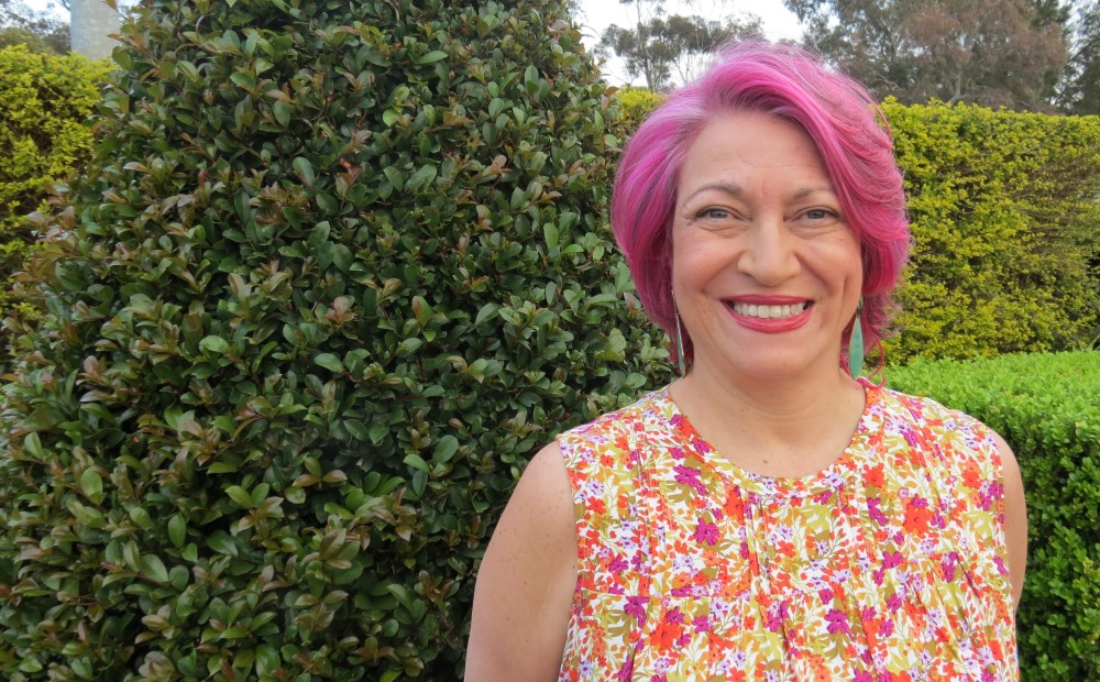 Woman with pink hair smiling at camera outside