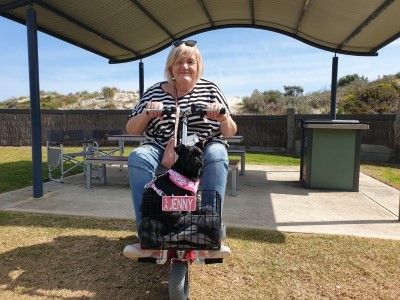 Woman on mobility scooter with pug in front basket