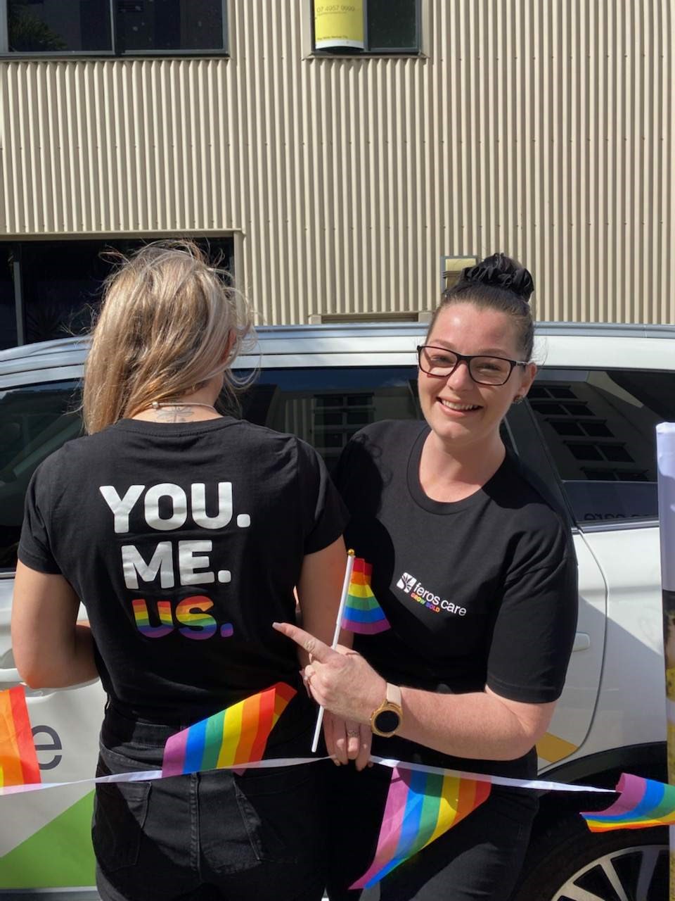 One young woman pointing at the back of a T-shirt of another, which says 