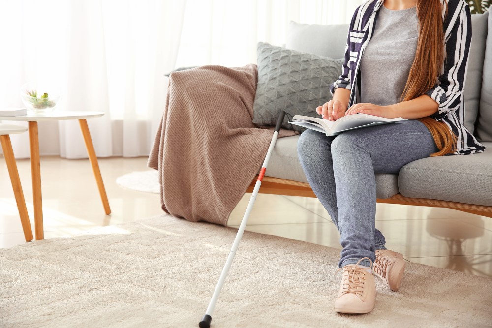 Blind woman sitting on couch and reading Braille book