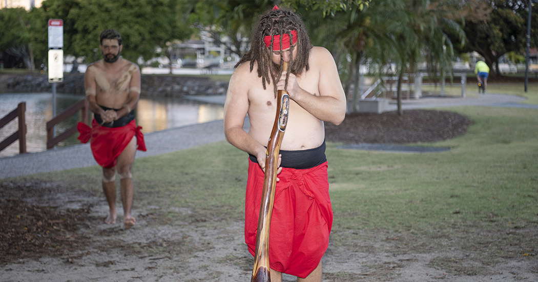 First Nations person playing didgeridoo