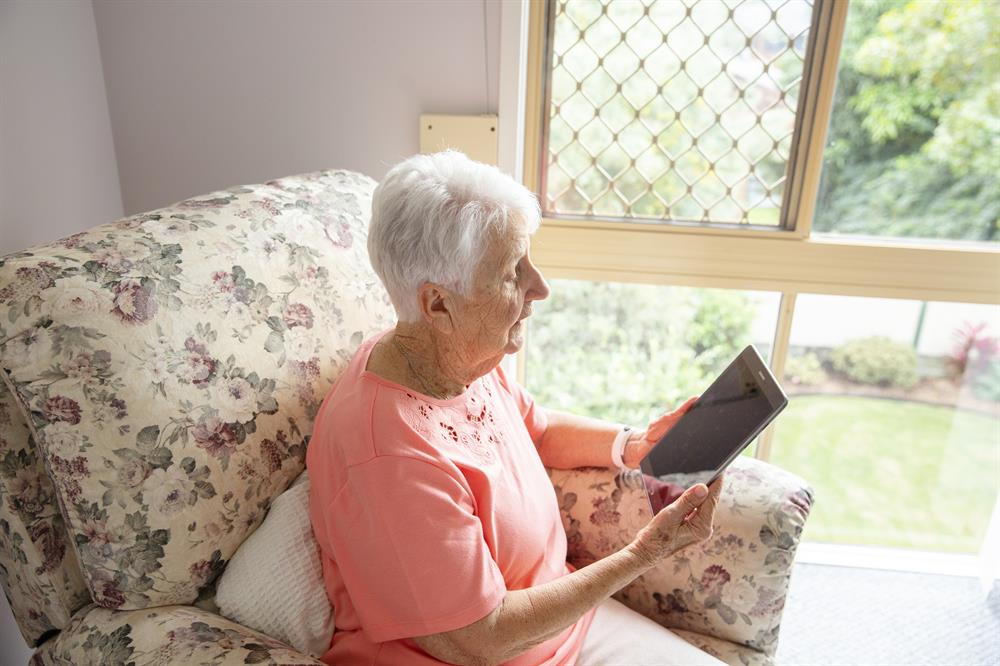 Senior lady on tablet Senior lady sitting in armchair and looking at tablet in hand