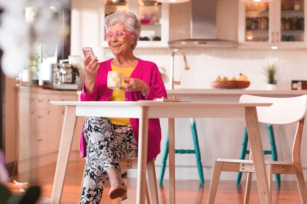 Lady with pink cardi having coffee looking at mobile phone Lady with pink cardi having coffee looking at mobile phone