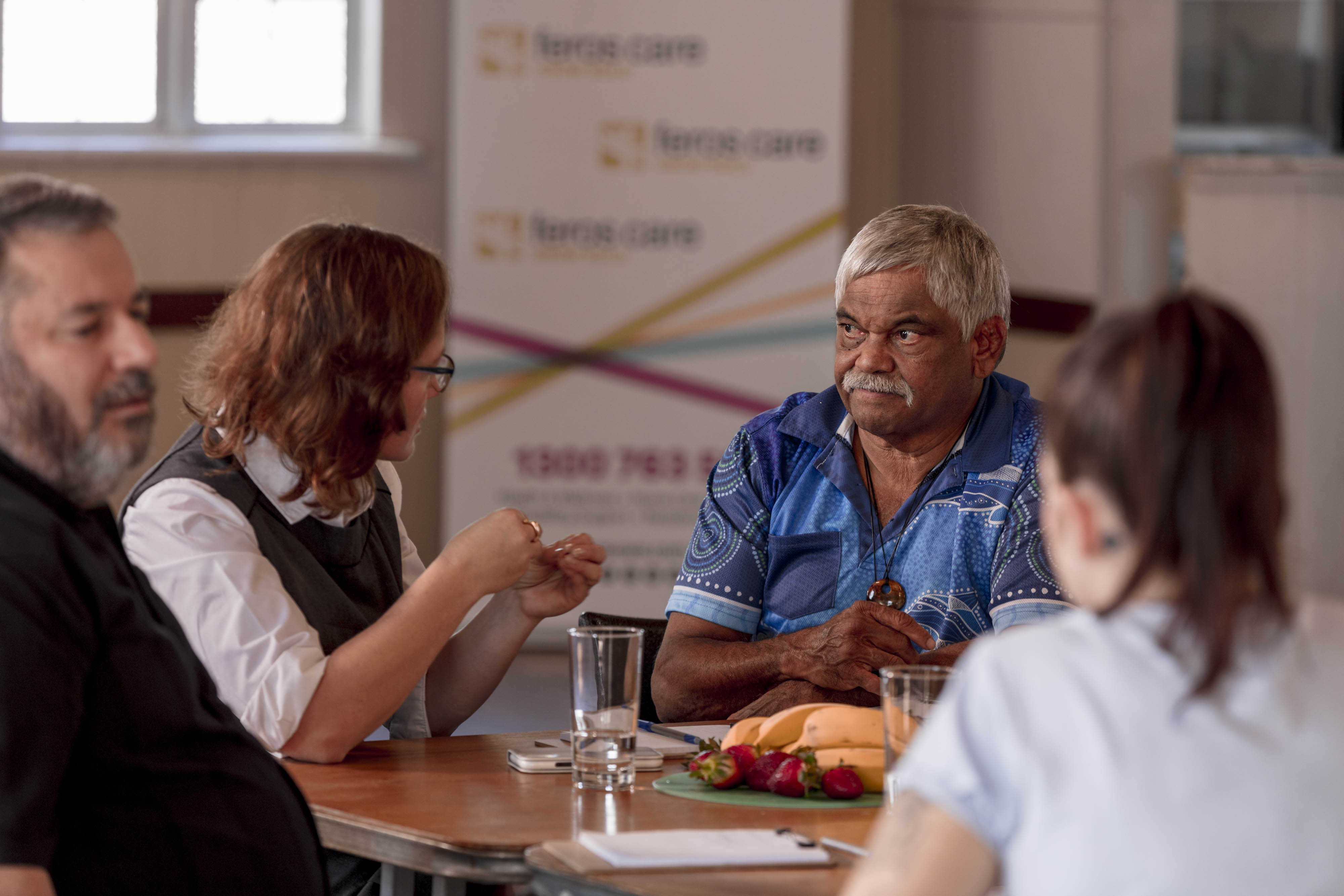 Aboriginal man and young woman talking at table