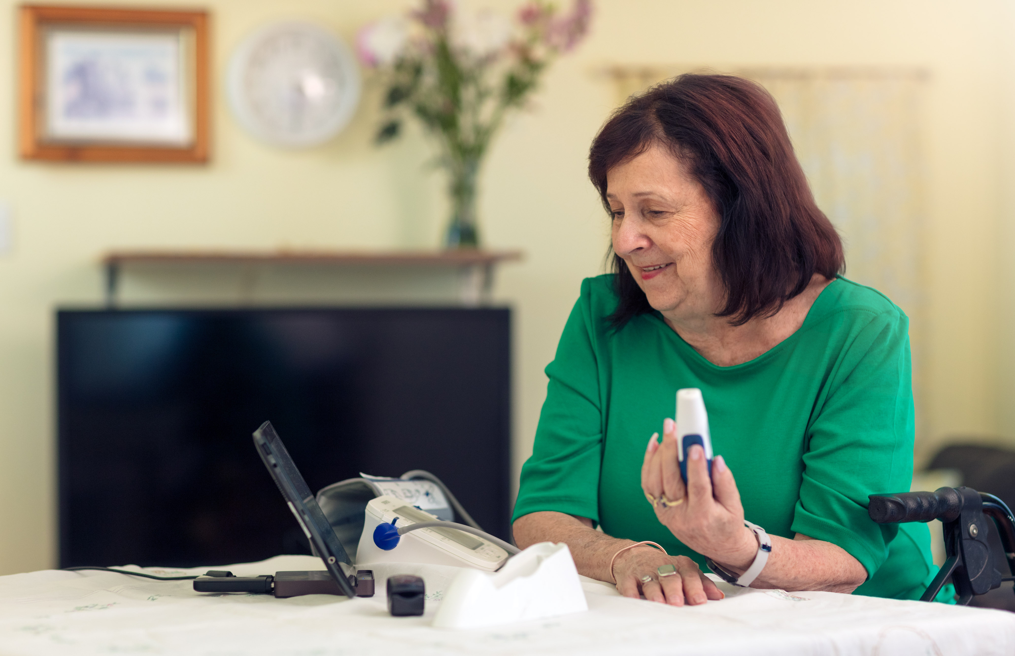 Senior lady using pulse oximeter at table