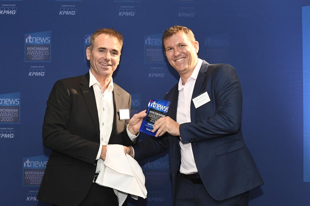 IT News Awards Two men shaking hands in front of IT news banner, one holding an award