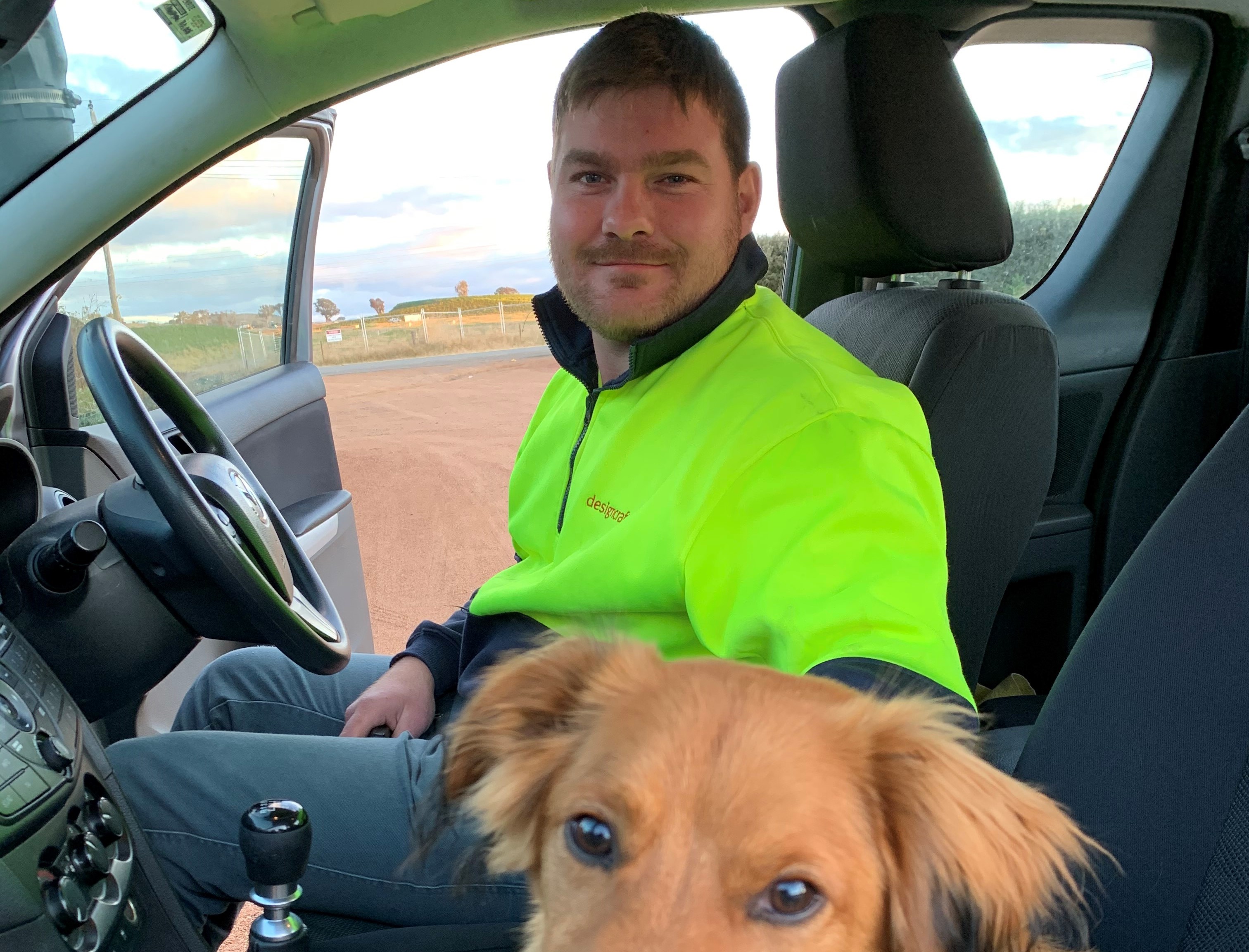 Man in car smiling at camera with dog