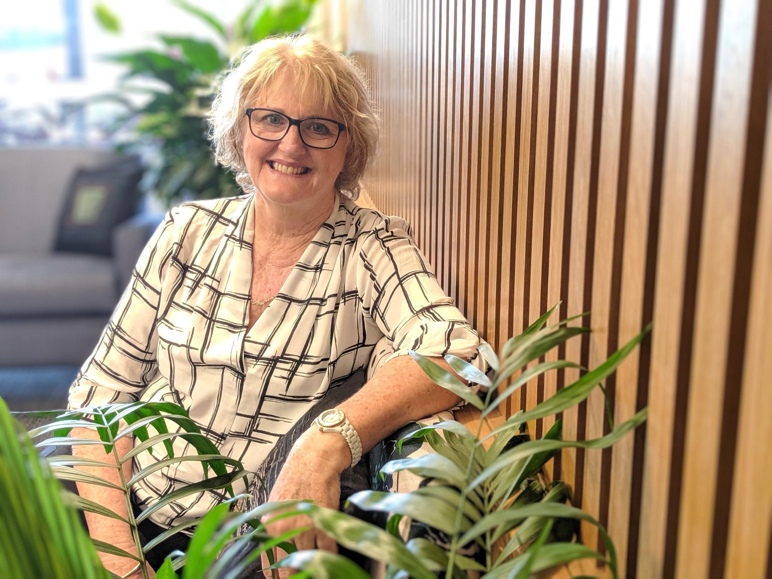 Lady with glasses sitting among house plants