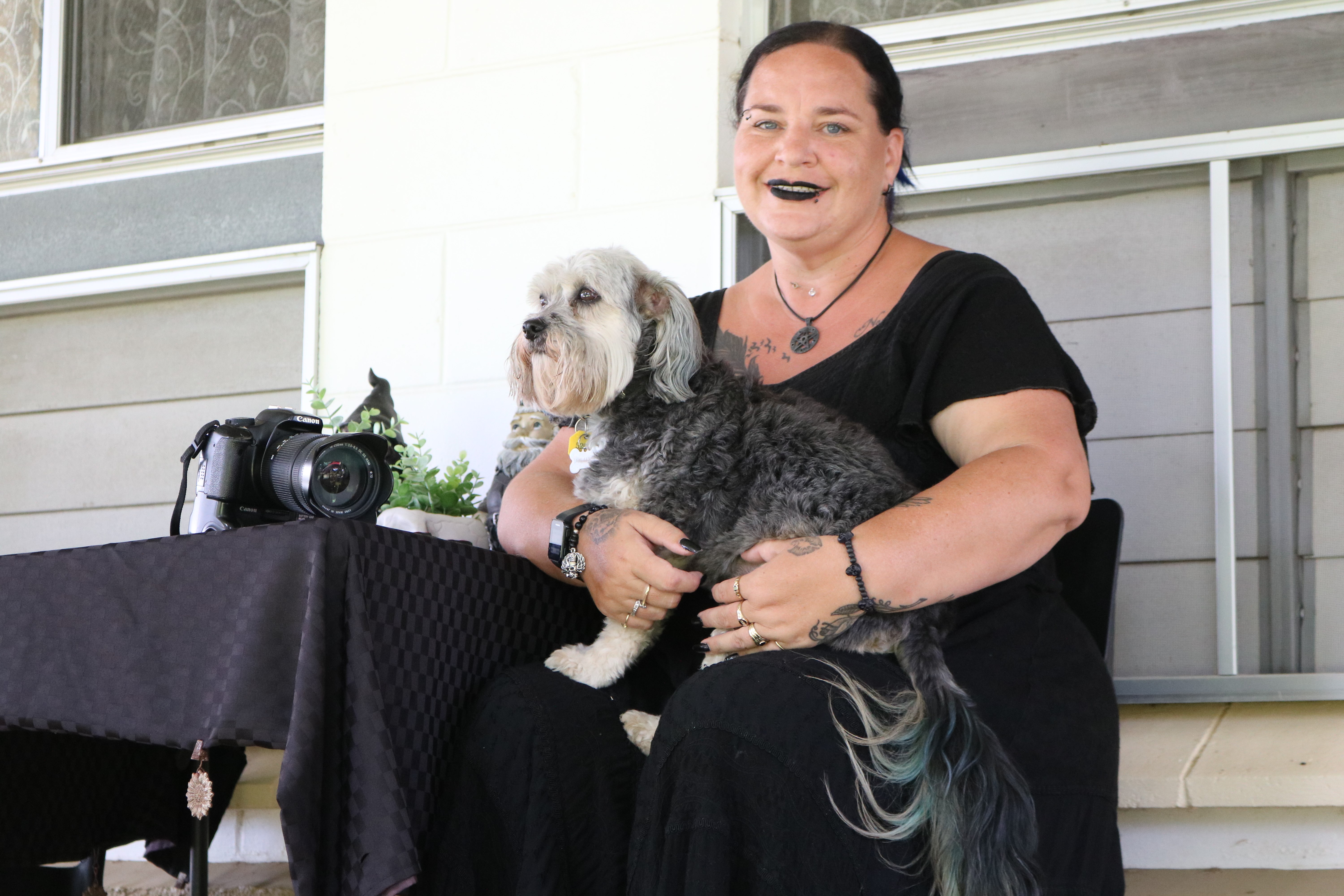 Woman sitting with dog in lap next to camera