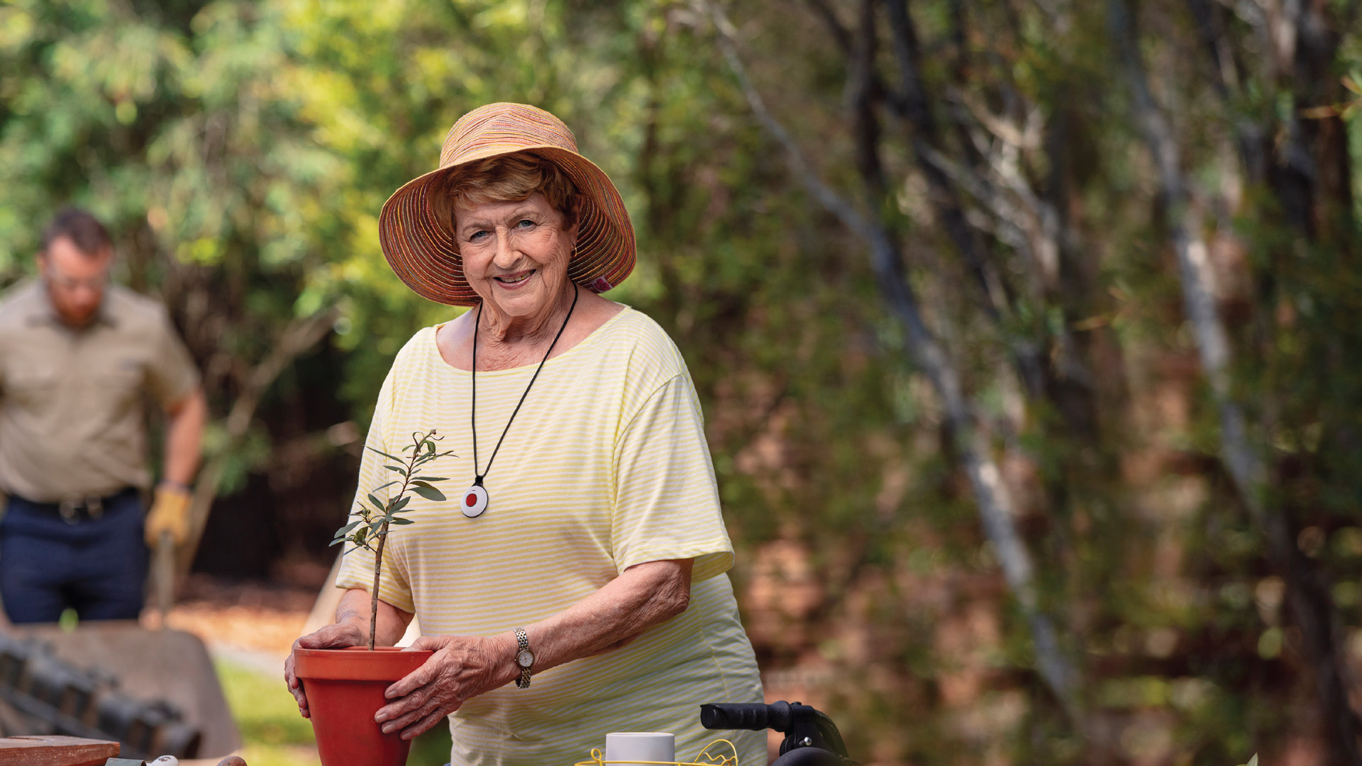 Elderly lady with personal alarm pendant standing in garden