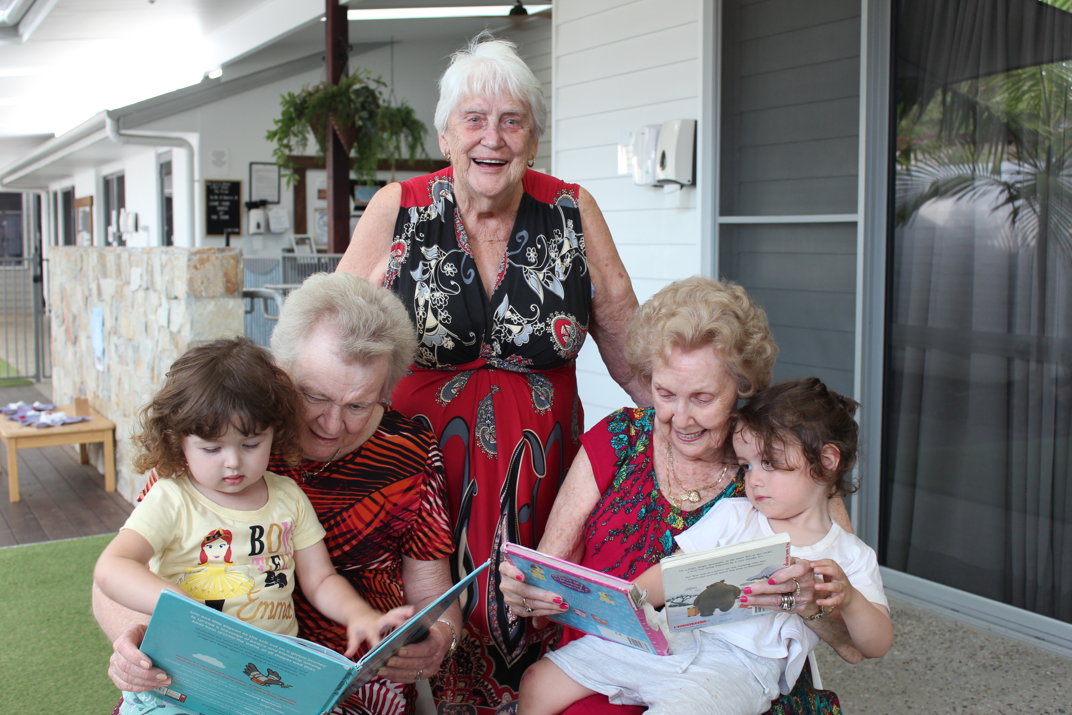 Three senior ladies reading to toddlers