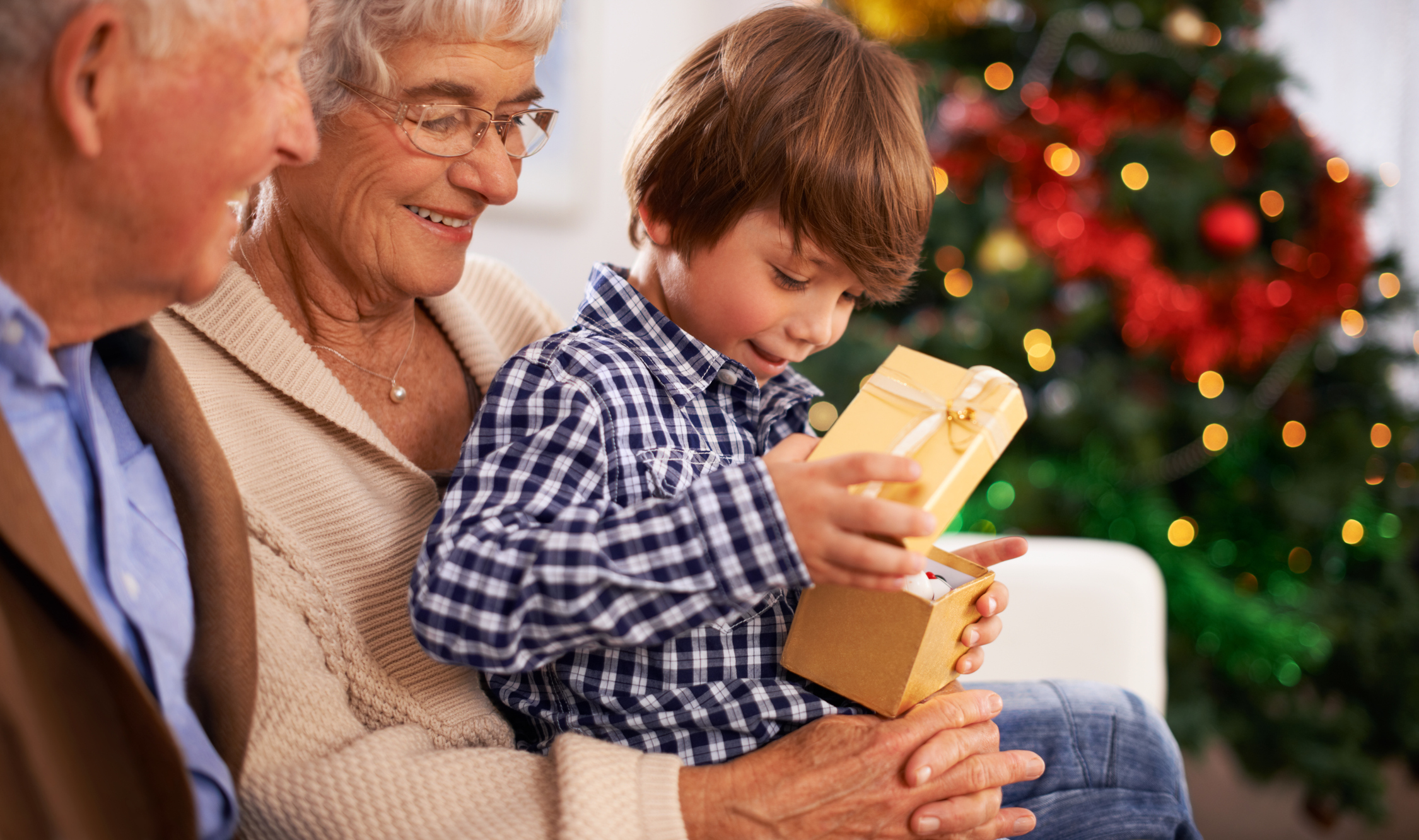 Kid opening present with grandparents at Christmas