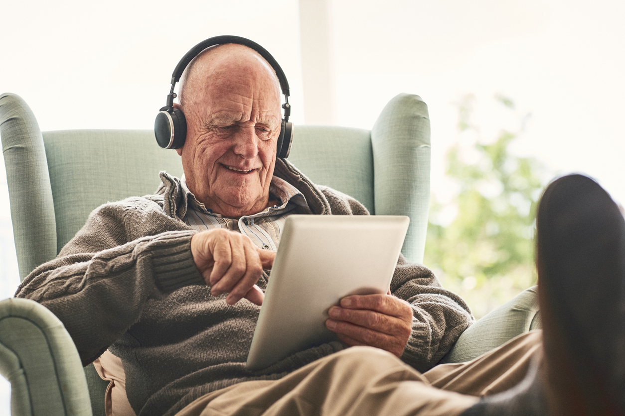 Elderly man with headphones and tablet