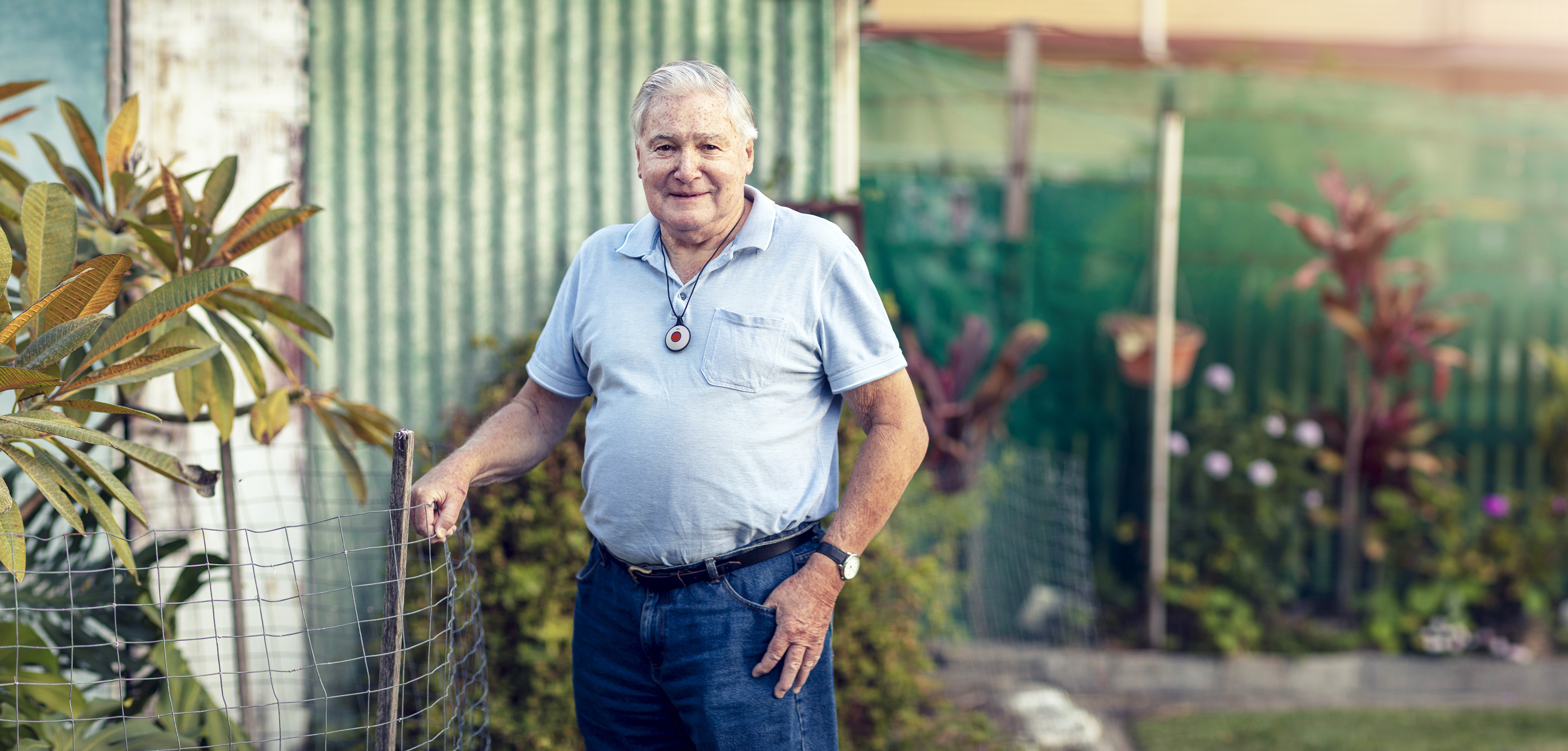 Senior man standing outside with personal alarm pendant around neck 