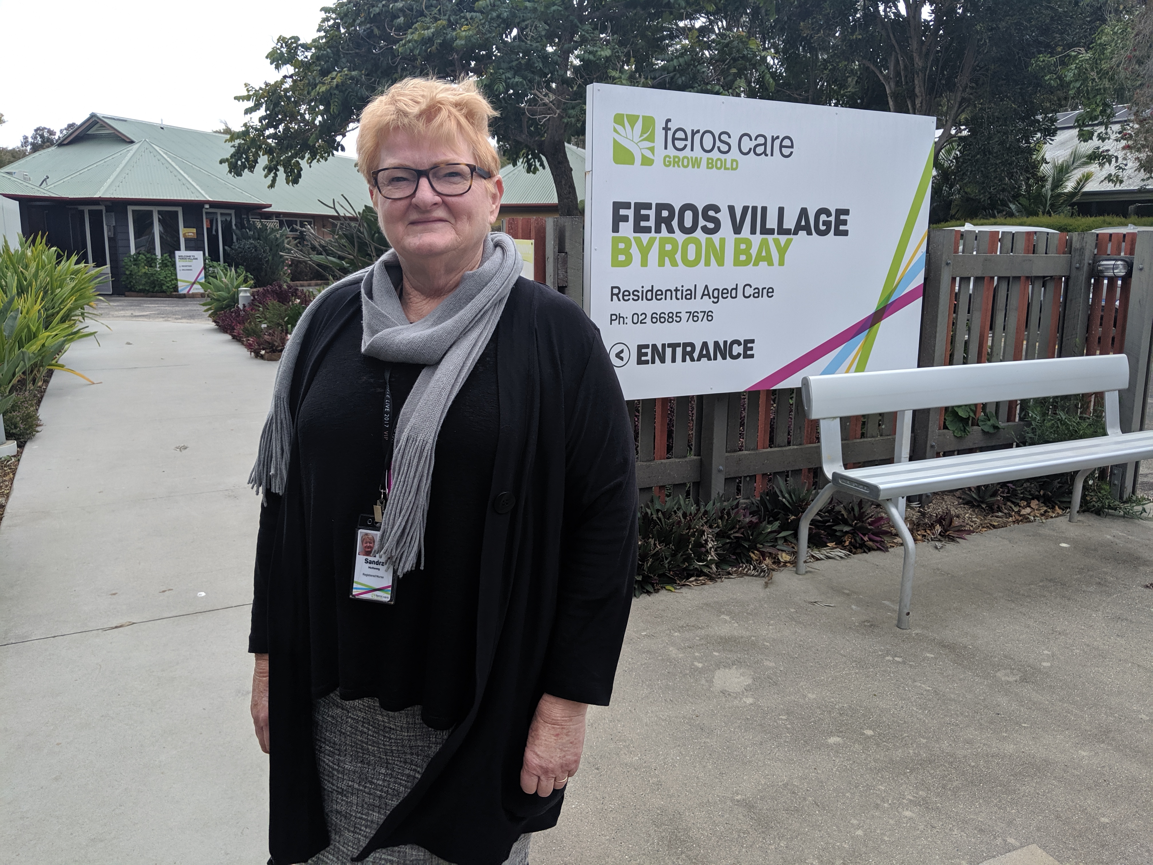 Woman standing in front of Feros Care Byron Bay Residential Village sign 