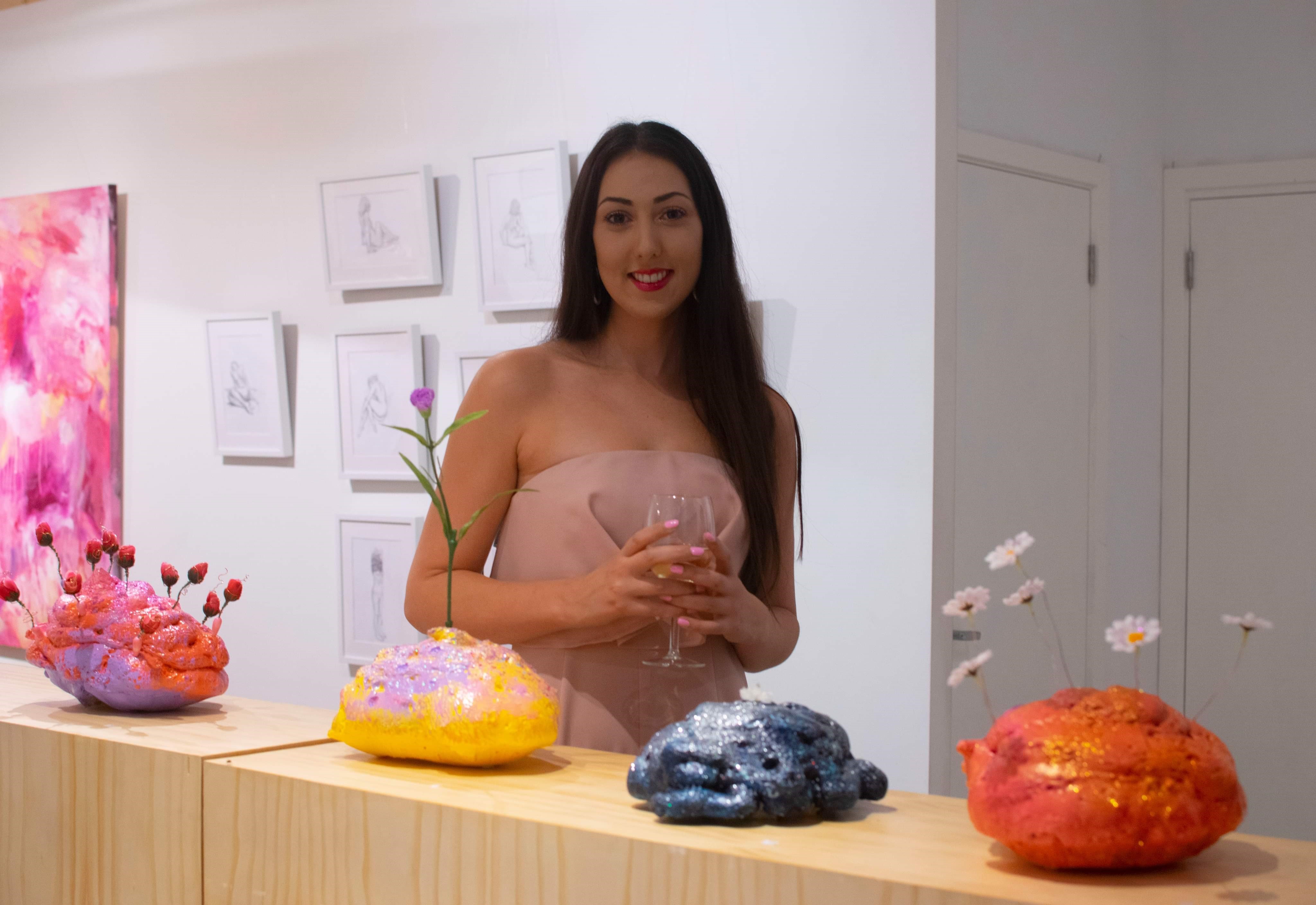 Woman smiling and holding a drink in an art gallery
