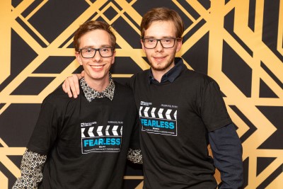 Two young men - both wearing black Fearless Films T-shirts and glasses - posing for a photo