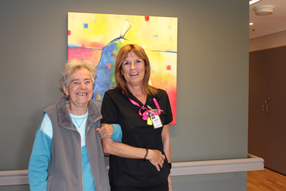 A senior lady and a middle aged woman linking hands and smiling