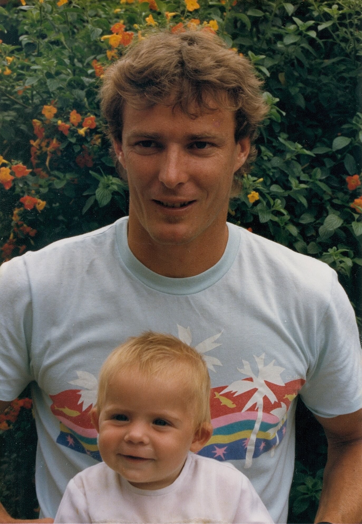 Old scanned film photo of a young man with a baby in his lap