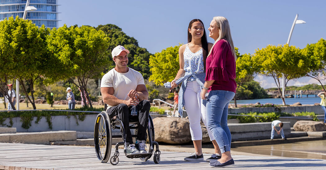 Man in a wheelchair, young woman and middle-aged woman on broadwalk